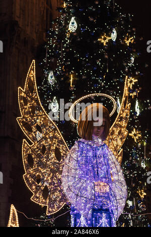 Beleuchtete Engel vor einem Weihnachtsbaum Stockfoto