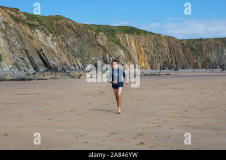 Ein kleiner Junge, der an einem leeren Strand in Großbritannien läuft. Stockfoto