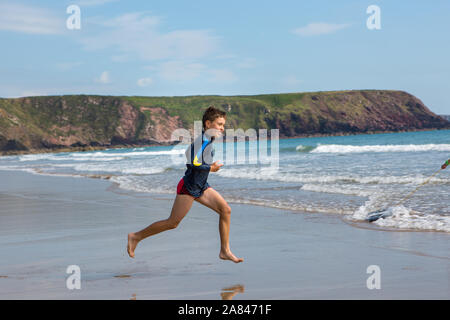 Ein kleiner Junge, der an einem leeren Strand in Großbritannien läuft. Stockfoto