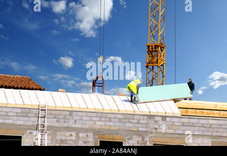 Festlegung der Dämmplatten auf dem Dach eines Hauses im Bau. Stockfoto