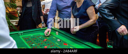 Gruppe von Menschen hinter Roulette Tisch in Luxus Casino. Freunde Poker spielen an den Roulette Tisch mit Maßband. Vegas Spiele Nachtleben lucky Konzept gewinnen. Banner Stockfoto