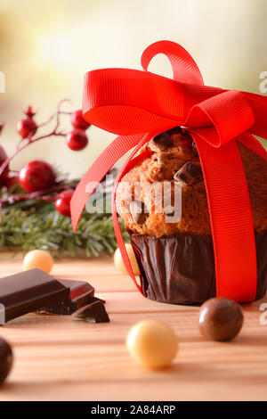 Chocolate Chip muffin auf Holztisch mit Weihnachten Objekte mit roten Schleifchen verziert. Vertikale Komposition. Vorderansicht. Stockfoto