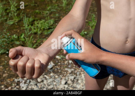 Jungen mit einem mückenspray. Menschen sprühen Insektenschutzmittel Haut outdoor. insect bite Schutz Stockfoto