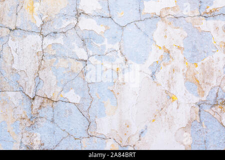 Hintergrund eines alten weißen und gelben und blauen feste Wand mit abblätternder Farbe und Risse gemalt. Stockfoto
