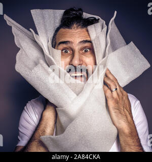 Mann mit langen Haaren und Bart schreit in Kunststoff verpackt. Sensibilisierung auf Kunststoff Übernutzung. Stockfoto