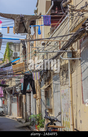 Elektrische Leitungen und Wäsche in einer engen Straße in der alten Viertel von Shanghai. Stockfoto