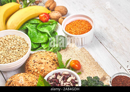 Einstellen der hohen Ballaststoffe Gesundheit Nahrung Produktkonzept mit Obst, Gemüse, Vollkornbrot, Hülsenfrüchten, Getreide, Nüsse und seedson weißen Holzmöbeln hinterg Stockfoto