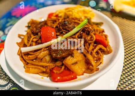 Traditionelle Mouthwatering Zentralasiatischen Uigurischen gebratene Nudeln Lagman Hauptgericht mit Gemüse auf einem weißen Teller Stockfoto