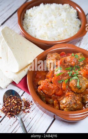Ein traditionelles türkisches Gericht mit gebackenen Fleischbällchen in Tomaten- und roter Pfeffersauce, serviert mit Orzo-Reis. Mini Sebzeli Kofte. Stockfoto