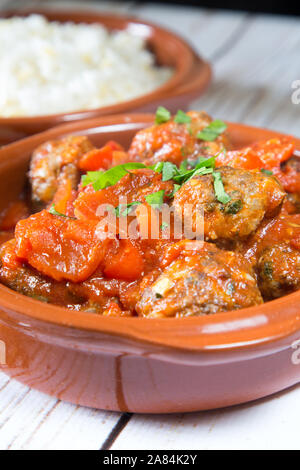 Ein traditionelles türkisches Gericht mit gebackenen Fleischbällchen in Tomaten- und roter Pfeffersauce, serviert mit Orzo-Reis. Mini Sebzeli Kofte. Stockfoto