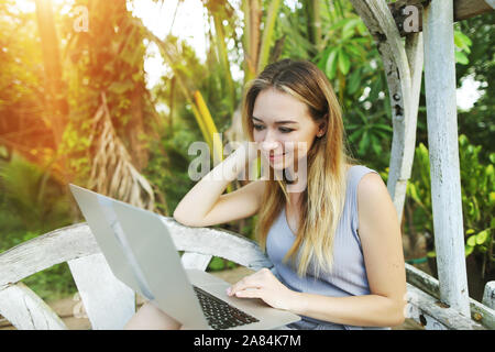 Frau mit Notebook für die Wiedergabe von film mit Sonnenschein grüne Palmen in Thailand, Phuket reisen Stockfoto