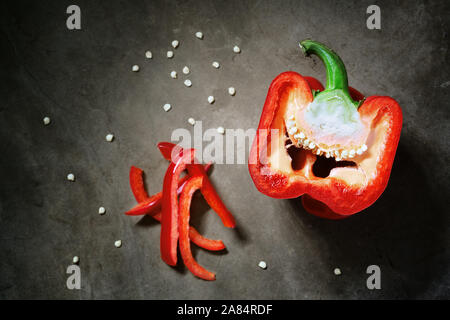 Eine rote Paprika auf dunklen Moody Hintergrund geschnitten in der Hälfte mit einer Ansicht von oben. Capsicum Stockfoto