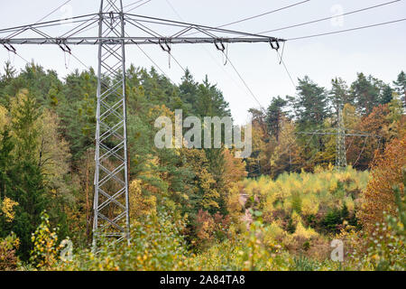 Hochspannungs-Stromleitungen und Hochspannungsmasten Transport elektrischer Energie in einer Gasse durch einen wunderschönen herbstlichen Wald. In Franken/Bavari gesehen Stockfoto