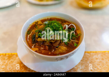 Traditionelle Mouthwatering Zentralasiatischen uigurischen Lagman Suppe, Hauptgericht mit Gemüse auf einem weißen Teller Stockfoto