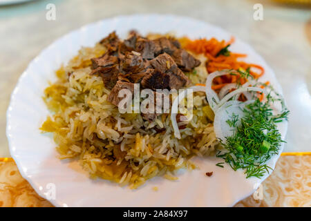 Die traditionellen Zentralasiatischen Kasachstan Stil Mouthwatering Lamm Plov mit gehackten Zwiebeln auf eine weisse Platte Stockfoto