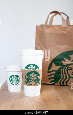 Kiew, Ukraine/November 06, 2019: Starbucks Kaffee nehmen Sie Tassen mit papiertüte auf Holz- zähler Tabelle. American global Kaffee und Kaffeehaus Stockfoto