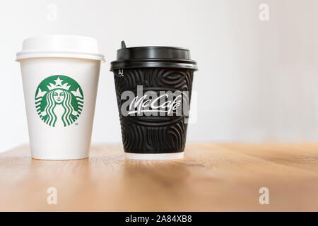 Kiew, Ukraine/November 06, 2019: eine Tasse Kaffee von Starbucks und McDonald's Kaffee auf Holztisch auf hellen Hintergrund. Marke Konfrontation, Kunde Stockfoto