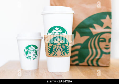 Kiew, Ukraine/November 06, 2019: Starbucks Kaffee nehmen Sie Tassen mit papiertüte auf Holz- zähler Tabelle. American global Kaffee und Kaffeehaus Stockfoto