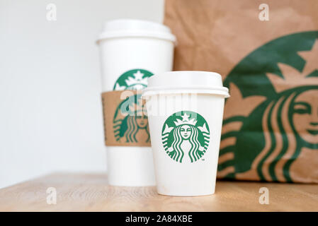 Kiew, Ukraine/November 06, 2019: Starbucks Kaffee nehmen Sie Tassen mit papiertüte auf Holz- zähler Tabelle. American global Kaffee und Kaffeehaus Stockfoto