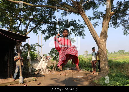 Bangladesch Kinder spielen 1 Nov2019, Ein Kind schwingt in seinem Kopf, um einen Baum zu schütteln. Das Bild nahm purbachal.© Nazmul Islam/Alamy Live News. Stockfoto