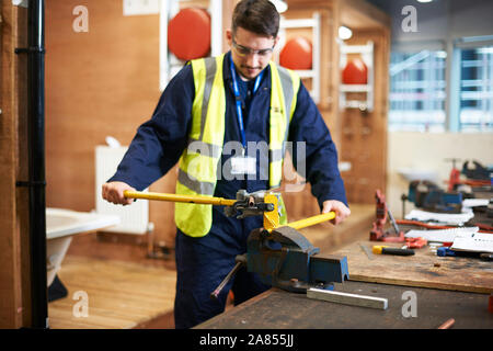 Junge männliche Kursteilnehmer über vice Grip im Shop klasse Workshop Stockfoto