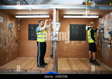 Männliche Elektriker Studenten üben in Werkstatt Stockfoto