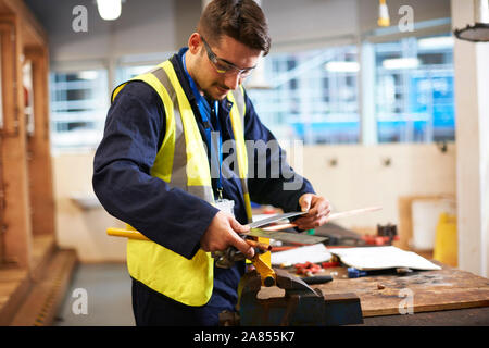 Männliche Kursteilnehmer über Tischler Regel im Shop klasse Workshop Stockfoto