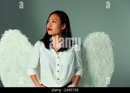 Serene, neugierige junge Frau mit Angel Wings Stockfoto