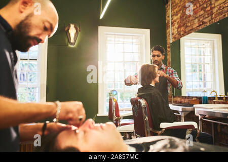 Männliche Friseure arbeiten in Barbershop Stockfoto