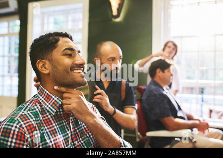 Lächelnd männlichen Kunden Kontrolle rasierten Gesicht in Barbershop Stockfoto