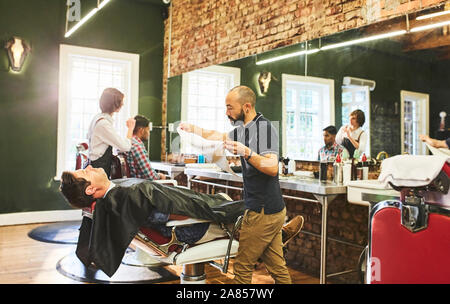 Männliche friseur Vorbereiten der Dampf Gesicht des Kunden vor der Rasur im barbershop Stockfoto