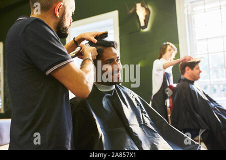 Lächelnd Mann empfangen von neuen Haarschnitt im barbershop