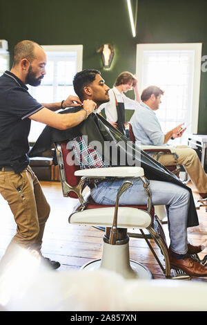 Männliche friseur Vorbereitung Kunden für Haarschnitt im barbershop Stockfoto