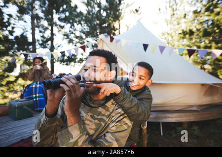 Glücklich, neugierig Vater und Sohn mit dem Fernglas auf dem Campingplatz Stockfoto