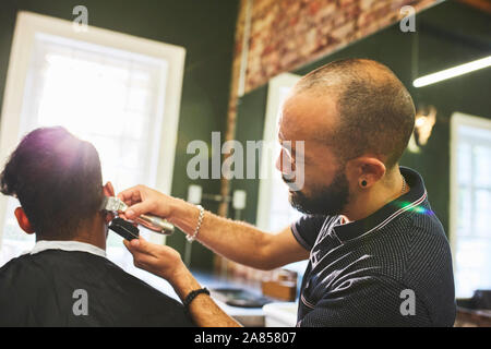 Männliche Friseur mit Trimmern geben Kunden Haarschnitt im barbershop Stockfoto