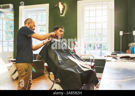 Männliche Friseur dem Kunden einen Haarschnitt in Barbershop Stockfoto