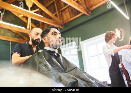 Männliche Kunde bekommt einen Haarschnitt in Barbershop Stockfoto