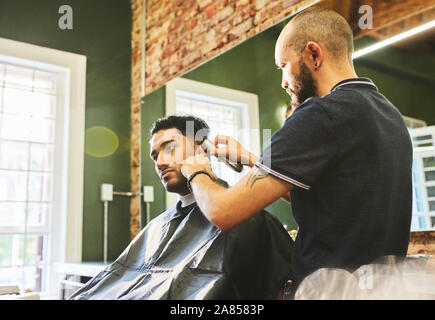 Männliche Friseur dem Kunden einen Haarschnitt in Barbershop Stockfoto