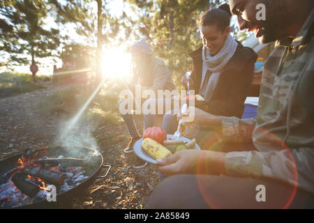 Familie essen bei Sunny campingplatz Lagerfeuer im Wald Stockfoto