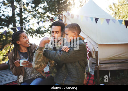 Verspielt Vater flexing Bizeps Muskeln für Sohn am Campingplatz Stockfoto