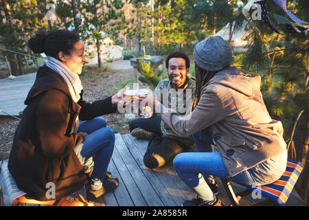 Gerne Freunde, Wein trinken und auf einem Campingplatz im Wald Stockfoto