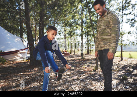 Vater, Sohn brechen Kindling auf einem Campingplatz im Wald Stockfoto