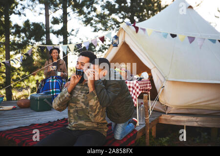Neugierig, Vater und Sohn mit Fernglas außerhalb Jurte auf dem Campingplatz Stockfoto