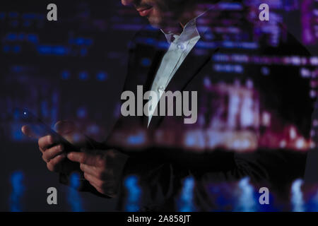 Double Exposure Geschäftsmann mit smart phone gegen die Lichter der Stadt in der Nacht Stockfoto