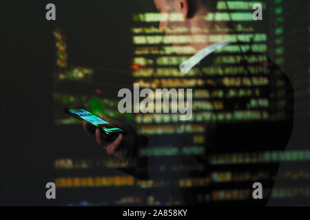 Double Exposure Geschäftsmann mit smart phone gegen Hochhaus in der Nacht Stockfoto