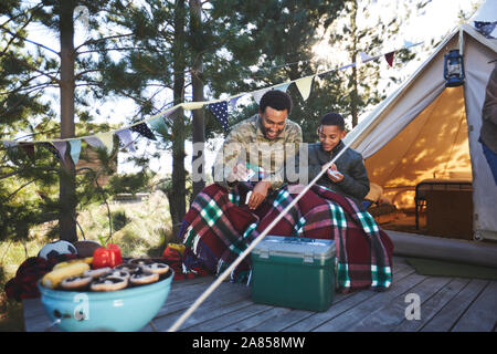 Vater und Sohn Karten außerhalb Jurte auf dem Campingplatz Stockfoto