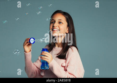 Fröhlicher, verspielter Mädchen mit Bubble wand bläst Seifenblasen Stockfoto