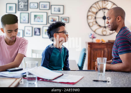 Vater und Söhne sprechen, Hausaufgaben in der Küche Stockfoto