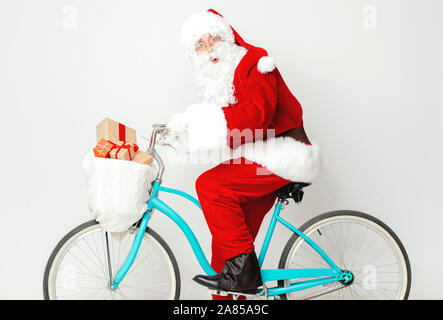 Überrascht Santa Claus reiten ein Fahrrad mit präsentiert Stockfoto