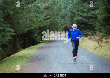 Active Senior mann Jogging auf Trail im Wald Stockfoto